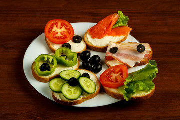 White plate with assorted sandwiches on a wooden table.