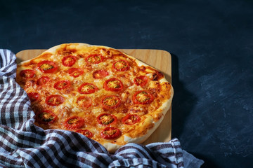 Freshly baked homemade pizza Margherita lies on a black background.