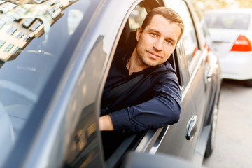 Young man in the dark swordsman driving sobsvenno car peeking out and looking at the camera
