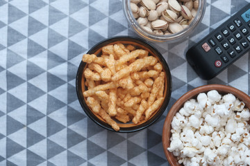 popcorn, chops in bowl and tv remote on table.