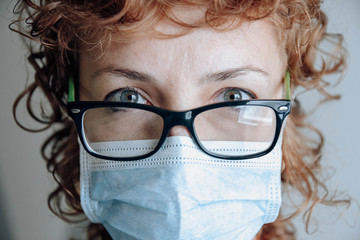 readhead woman with glasses and surgical mask