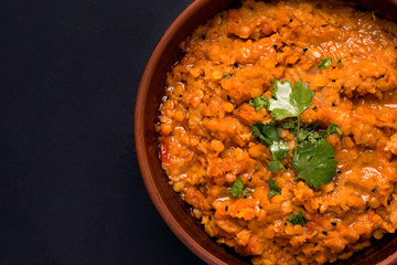 Dhal traditional vegetarian red lentil bean soup with cilantro on a black background. Copy space