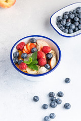 Fresh organic fruit salad with Chia seeds. Healthy breakfast set on grey background. The concept of delicious and healthy food. Top view, copy space