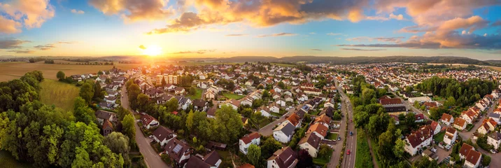 Fototapeten Luftpanorama einer kleinen Stadt bei Sonnenaufgang, mit herrlichem buntem Himmel und warmem Licht © Smileus