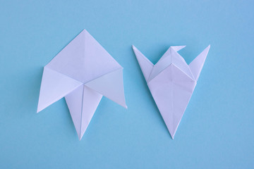 Handmade white trendy geometric polygonal paper origami fish on blue background.Step 3.