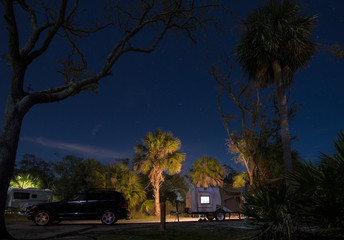 Teardrop camper in campsite at Hunting Island State park, South Carolina at night with stars.