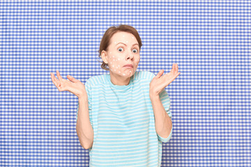 Portrait of confused girl with white spots of cosmetic product on face