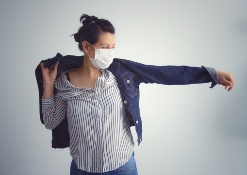 Young Woman Wearing A Mask Putting On A Jacket To Go Outside After Quarantine. End Of Virus Crown