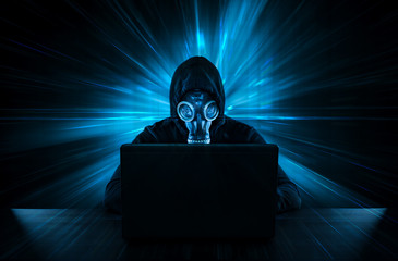 Male thief in gas mask stealing data from computer