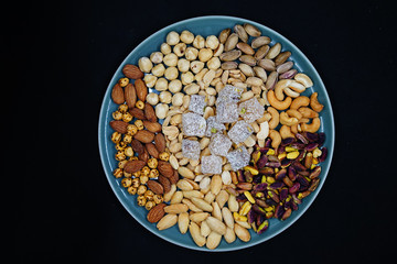 mixed nuts from above. Nuts of granite on a black background. Nuts shot from the top. nuts on a black background. peanut, cashew, roasted chickpea, hazelnut, pistachio, almond, roasted chickpea.