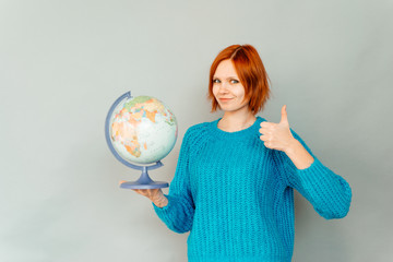 Image of young happy woman isolated over grey background holding globe
