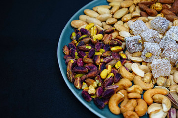 mixed nuts from above. Nuts of granite on a black background. Nuts shot from the top. nuts on a black background. peanut, cashew, roasted chickpea, hazelnut, pistachio, almond, roasted chickpea.