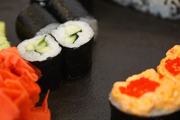 Sushi roll with cucumber, ginger, wasabi. Sushi menu. Japanese food on a black plate.