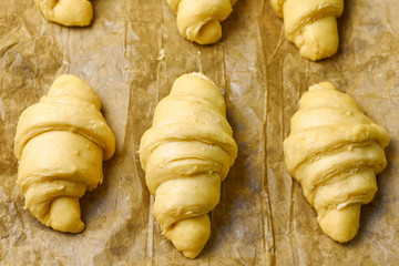 Top view of unbaked italian brioches on a baking paper. Homemade pastry from yeast dough. Production of french croissant.