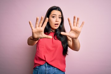 Young brunette woman wearing casual summer shirt over pink isolated background doing stop gesture...