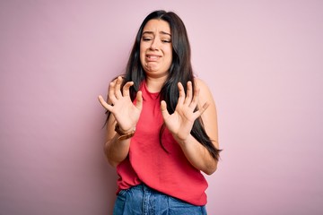 Young brunette woman wearing casual summer shirt over pink isolated background disgusted...