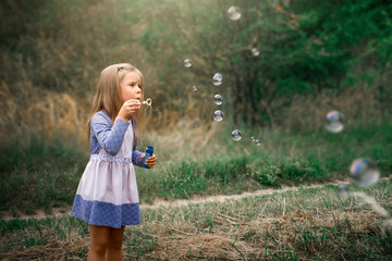 little girl blows soap bubbles