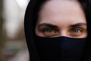 Young woman wearing face mask. Handsome woman in black hoodie wear black medical mask. Close up portrait. Pandemic coronavirus covid-19 quarantine period concept.