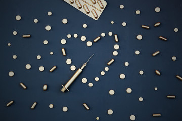Gold tablets and syringes on a dark background.