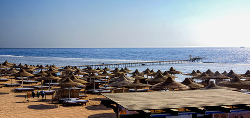 Beach with sun loungers and a wooden pier, on the seashore.