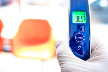 Man hand with glove holding digital non contact thermometer