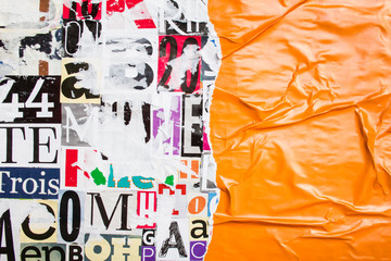 Torn and crumpled orange glossy paper poster on bright colorful collage of magazine paper pieces...