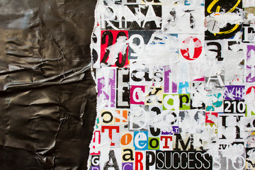 Torn and crumpled black glossy paper poster on bright colorful collage of magazine paper pieces and...