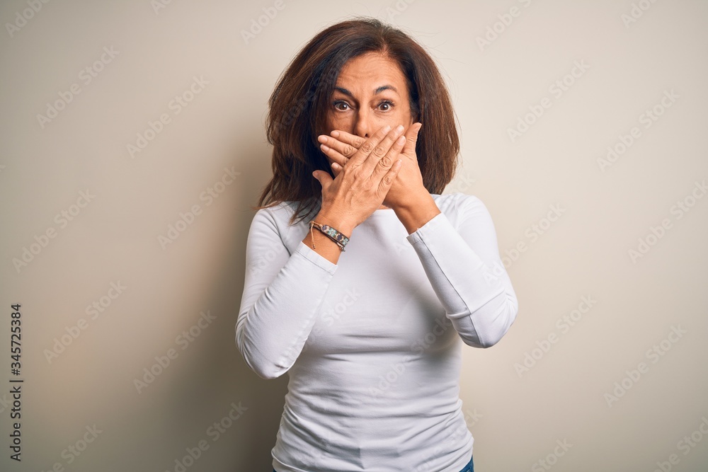 Poster Middle age beautiful woman wearing casual t-shirt standing over isolated white background shocked covering mouth with hands for mistake. Secret concept.