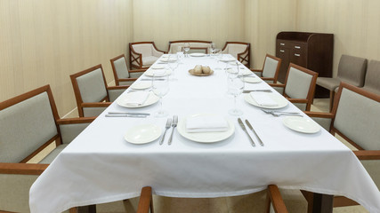 Big table with white tablecloth, plates and cutlery