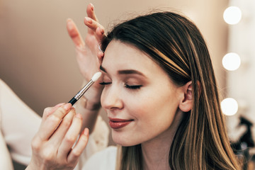 Fototapeta premium Make up artist doing professional make up of beautiful young woman.