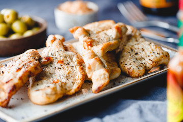 Grilled turkey escalopes with hot sauce on a table.
