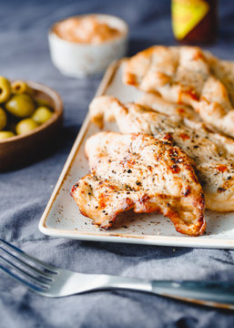 Grilled turkey escalopes with hot sauce on a table.