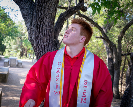 Young, attractive boy with red hair taking graduation pictures
