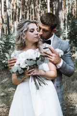 the bride and groom embrace in the forest on the wedding day. wedding ceremony. selective focus. film grain.