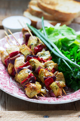 Chicken kebabs with vegetables served with various herbs and sauce.