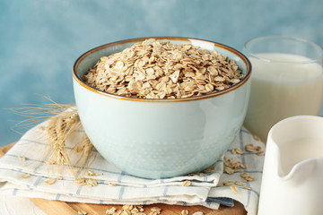 Composition with oatmeal flakes and milk on white table. Cooking breakfast