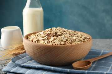 Composition with oatmeal flakes and milk on gray background. Cooking breakfast