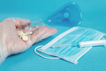 medical mask, syringe, mask for inhalation and tablets close on the blue background. hand holds pills. Coronavirus, flu
