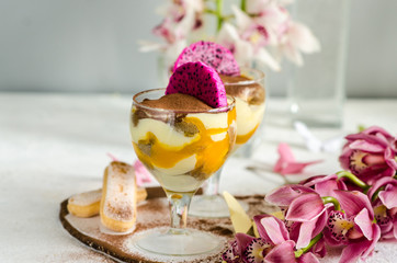 Tiramisu creme dessert with mango in a glass. Dessert and orchid decoration on the table