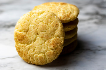 A stack of snickerdoodle cookies on a white and  grey marble surface.  Blurry background.  Close up view of cookie facing camera.