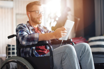 Handicapped man using tablet and earphones