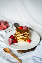 Close-up delicious pancakes, with strawberries and syrup on a light background. Sweet syrup flows from a stack of pancake