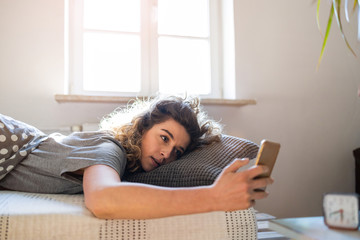 Obraz premium Young woman using smartphone in bed 