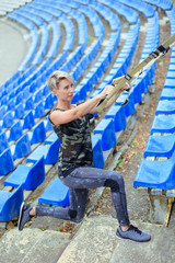 young girl doing exercises outdoors using slings, TRX loop