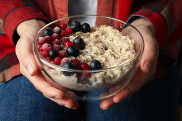 Woman holds bowl with oatmeal porridge with fruits. Close up