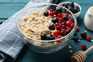 Towel and bowl with oatmeal porridge and fruits on wooden background. Cooking breakfast