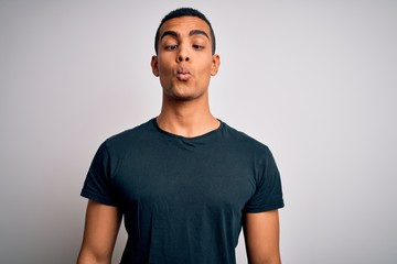 Obraz premium Young handsome african american man wearing casual t-shirt standing over white background making fish face with lips, crazy and comical gesture. Funny expression.