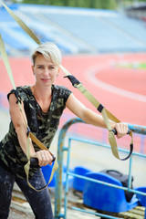 young girl doing exercises outdoors using slings, TRX loop