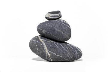 3 piedras con rayas blancas apiladas una sobre otra en forma de pirámide manteniendo el equilibrio.