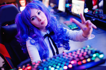Cosplay young beautiful woman with blue hair welcomes subscribers to stream for video games, neon...